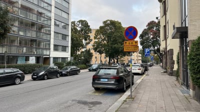 Bilar står parkerade vid en gata i Åbo. Närmast kameran finns en svart bil och en trafikskylt som förbjuder parkering förutom för bilar med CD-skylt.