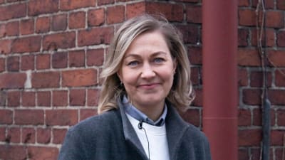 Anne Perälahti fotograferad vid en tegelvägg.