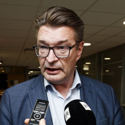 Pros ordförande Jarmo Malinen svarar på journalisternas frågor. Många mikrofoner är ställda mot honom.