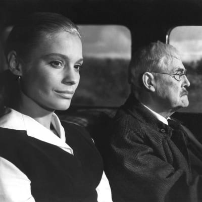 Svartvit bild ut Bergmans film Smultronstället som föreställer två personer i en bil.