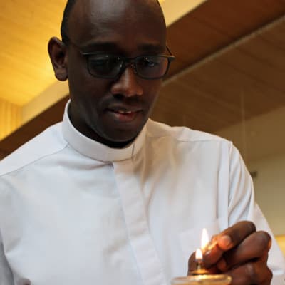Pyhän Ursulan seurakunnan kirkkoherra Jean Claude Kabeza sytyt kynttilaa