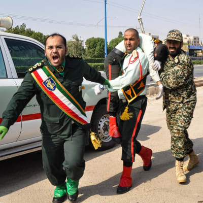 Iranska soldater bär bort en sårad kamrat efter attacken mot en militärparad i Ahvaz, lördagen 22.9.