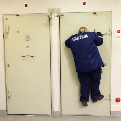 Väktare Ulpu Keränen kikar in i en cell.