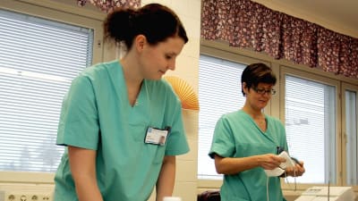 två sjukvårdare i arbetskläder tar hand om utrustning på ett sjukhus