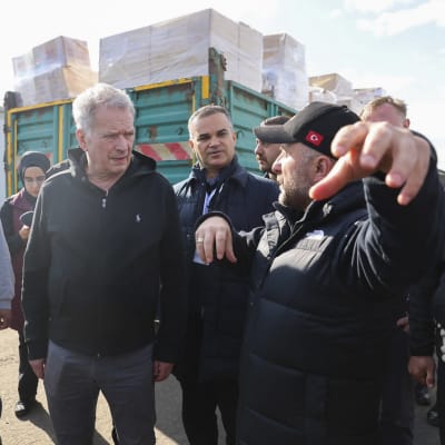 Sauli Niinistö kävelee kadulla seurueen kanssa. Vieressä kävelevä ihminen selittää, jotain Niinistölle. 