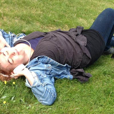 kvinna ligger i gräset med hörlurar