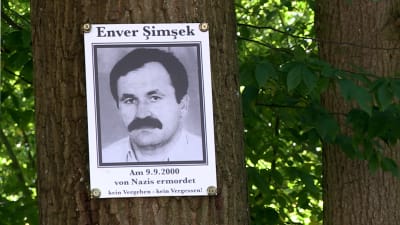 Svartvit bild på Enver Şimşek klistrat på ett träd.