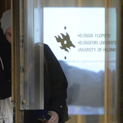 Studerande som går ut genom dörren vid Helsingfors universitet.