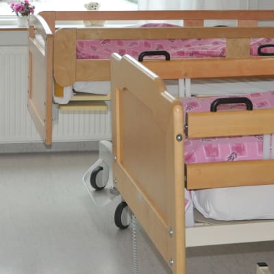 Två sängar med rosa överkast i ett rum på en bäddavdelning.