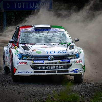 En rallybil kommer i hög hastighet på en grusväg.