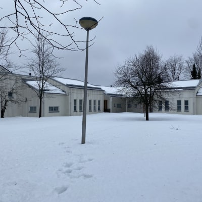 Lumisessa maisemassa päiväkoti Helsingin Töyrynummessa. Rakennuksessa valkoinen pystylaudoitus.