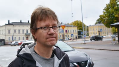 En man i svart jacka står ute på en gata i centrala Lovisa.