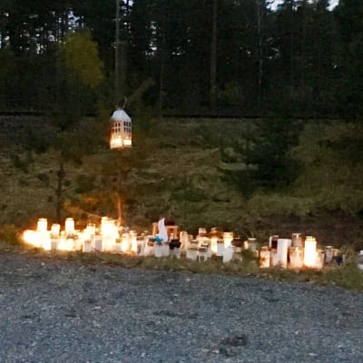 Många ljus brinner på marken vid en plankorsning till minne för fyra personer som avled i en olycka i slutet av oktober 2017.