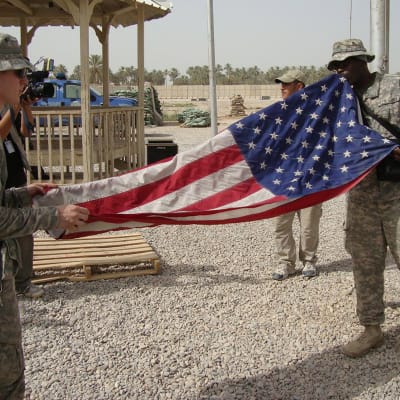 Amerikanska soldater viker ihop USA:s flagga i Irak.