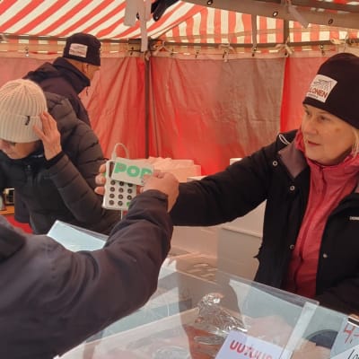 Asiakas ojentaa maksukorttia silakkamarkkinoiden kojulla.