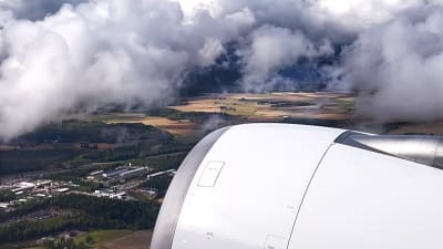 En turbin fotad från fönstret på ett flygplan, jord och moln syns genom fönstret.