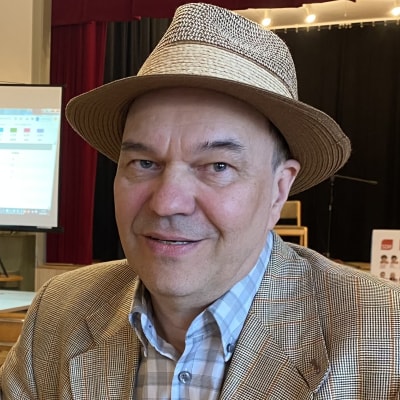 En medelålders man i kavaj och hatt.