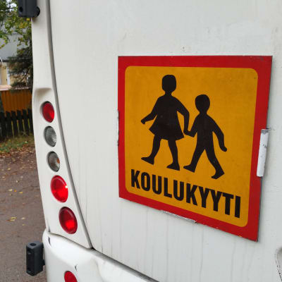Koulukuljetuksesta kertova koulukyyti-kyltti linja-auton perässä. 