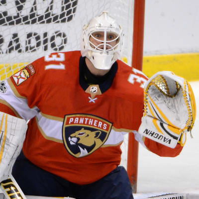 Rödklädde ishockeymålvakten Antti Niemi på knä för att rädda puck.