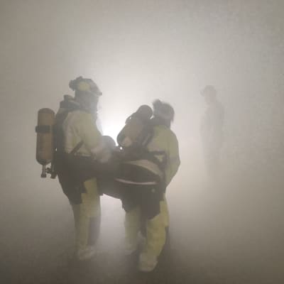 Pelastustyöntekijät harjoittelevat savun keskellä Pyhäsalmen kaivoksen uudessa harjoituskeskuksessa.