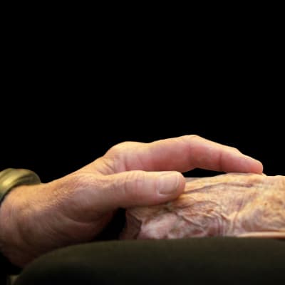 En mans hand håller i en åldrings hand