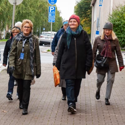 En grupp kvinnor vandrar på en stenlagd trottoar.