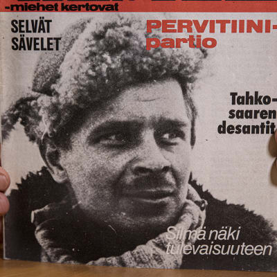 Mika Koivunen pitelee sormissaan Kansa taisteli -lehteä vuodelta 1978, jonka kannessa on hänen isänsä Aimo Koivusen kuva.