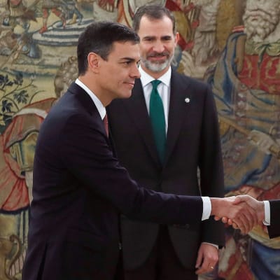 Spaniens nya premiärminister Pedro  Sánchez (till vänster) skakar hand med avgående premiärminister Mariano Rajoy.   Spaniens kung Felipe VI i bakgrunden.