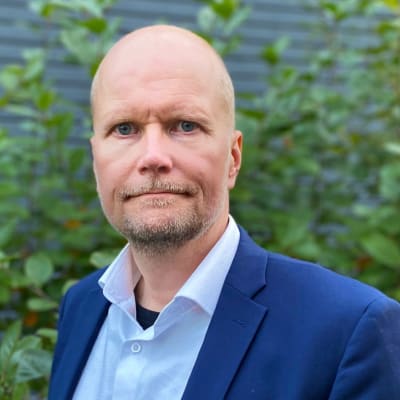 Kuva pukuun ja kauluspaitaan pukeutuneesta Mika Nevalaisesta.