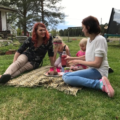 Familjen Wiklund har picknick på en filt på gräsmattan.