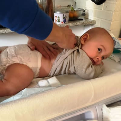 Vauvan selkää rasvataan hoitopöydällä.