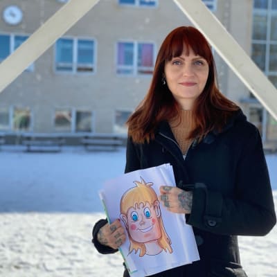 Ung kvinna med bild i handen på skolgård.