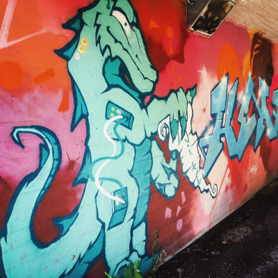 Graffititeos alikulkutunnelissa, jossa vihreäsävyinen lohikäärme.
