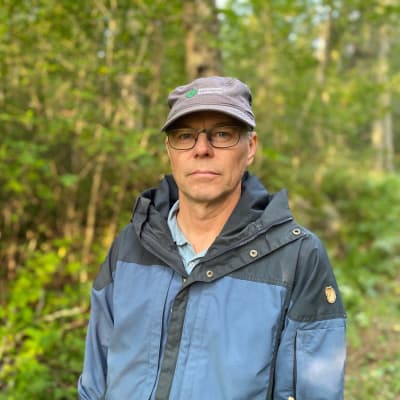 En man med keps i en skog. 