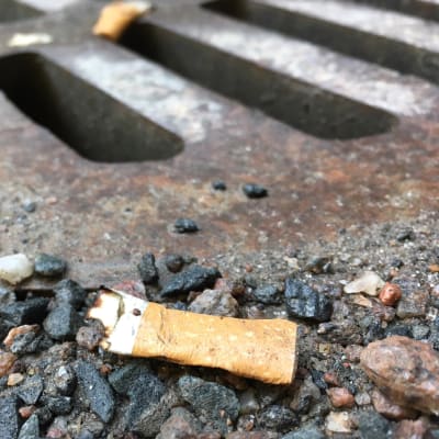 Tupakantumppi lojuu maassa sadevesiviemärin vieressä