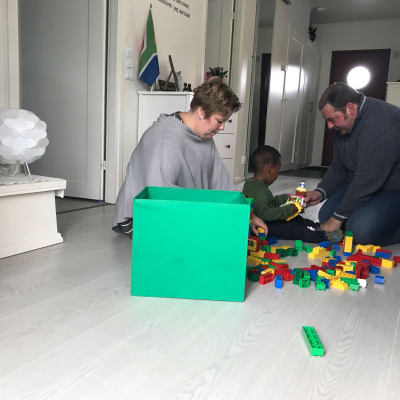 Åsa och Martin bygger lego med Denzel på golvet. 