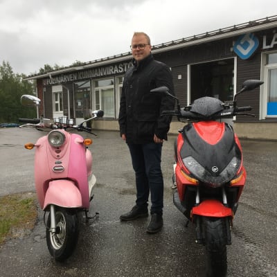 Polvijärven kunnanjohtaja Jari Tuononen seisoo kahden moposkootterin välissä.