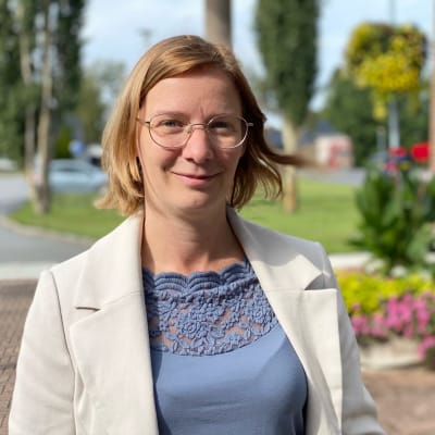 Kvinna med glasögon, neutralt leende. 
