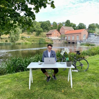 En man som sitter vid ett skrivbord på en gräsmatta i Billnäs bruk. 