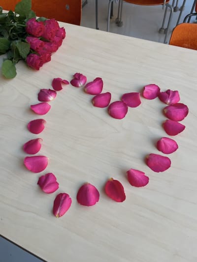En rosenbukett och rosenblad placerade som ett hjärta på bordet