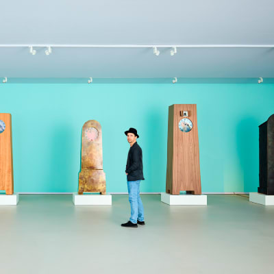 Muotoilija Maarten Baas kaappikellojen keskellä näyttelysalissa. Kellot kuuluvat Baasin Real Time -teossarjaan.