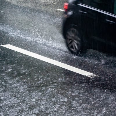 Henkilöauton takaosa sateisella kadulla.
