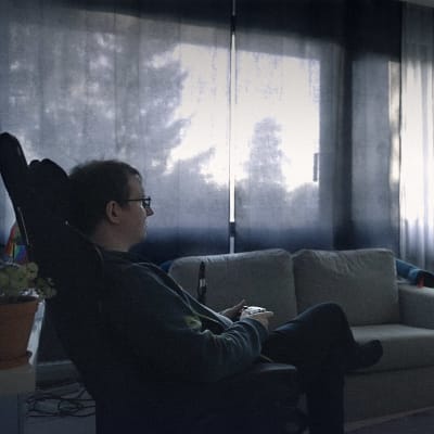 Riku Reponen istuu tuolissa ja pelaa kotonaan.