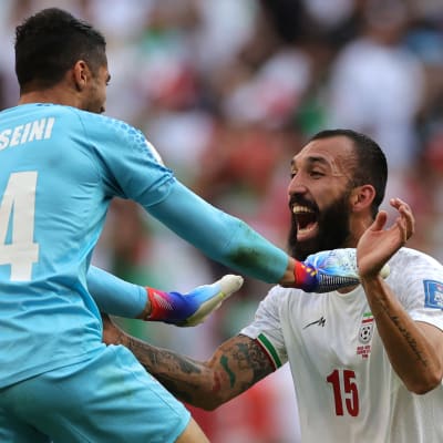 Irans målskytt Rouzbeh Cheshmi och målvakt Hossein Hosseini firar efter segern över Wales i fotbolls-VM.