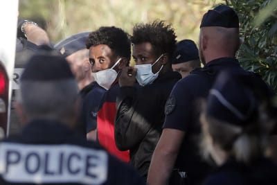 En grupp migranter som har anlänt till Frankrike och eskorteras av polis