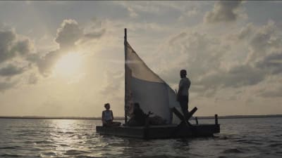 Huvudpersonerna i filmen sitter på en liten flotte och seglar mot horisonten.