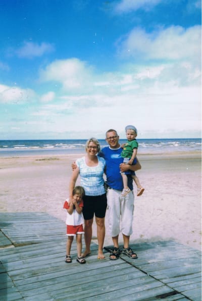 Hannu Räisän perhe ryhmäkuvassa hiekkarannala, taustalla meri.