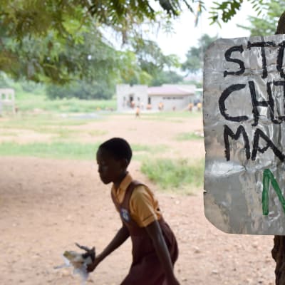 En skylt på en skolgård i Ghana uppmanar att upphöra med barnäktenskap.