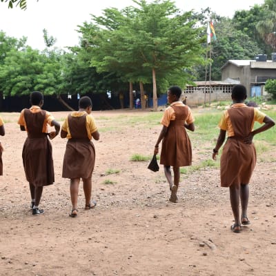 Fem flickor i skoluniform på väg mot skolan i Ghana. 