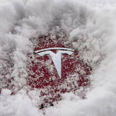 Ett Tesla-emblem syns under snön.